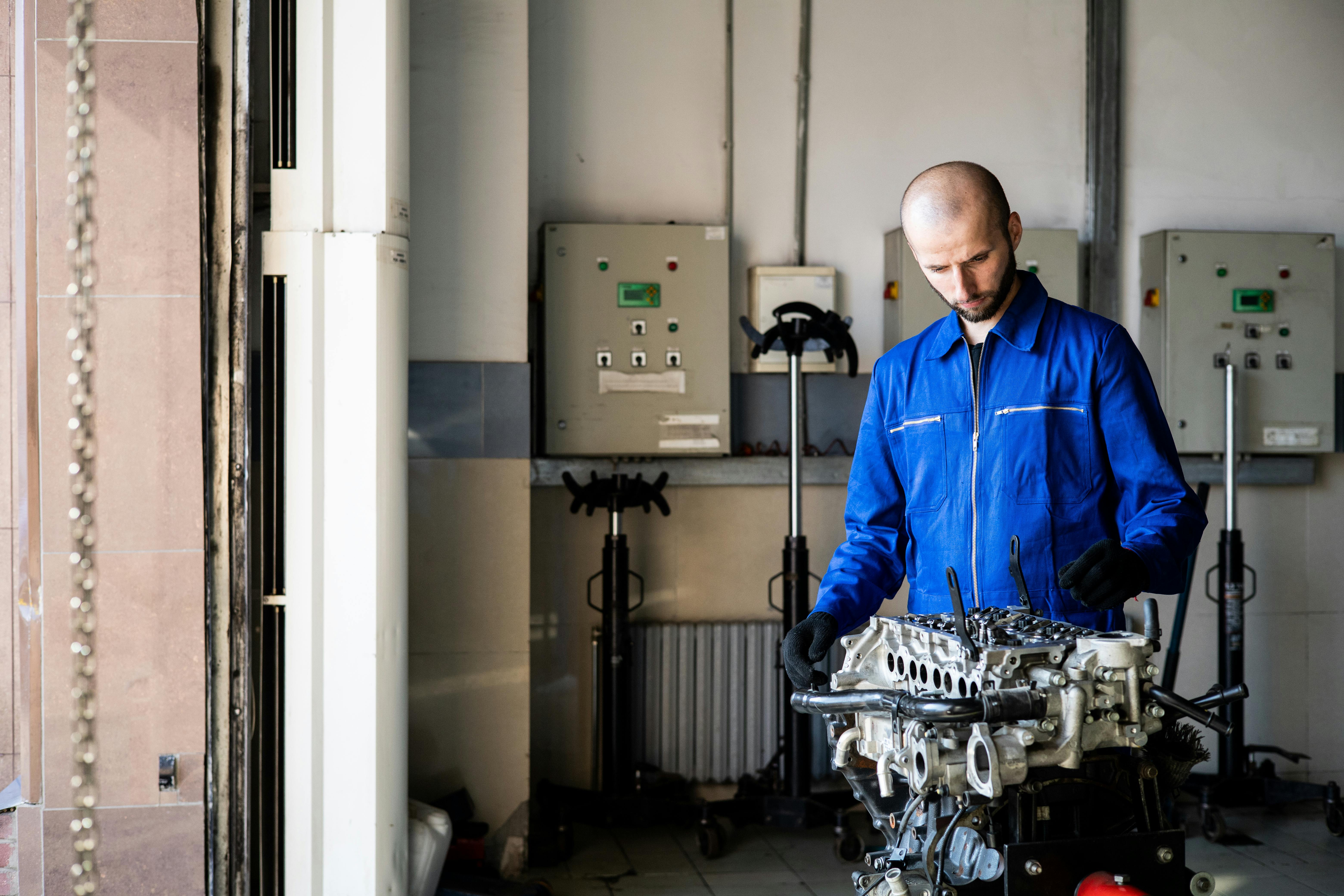 Automobilių serviso darbuotojas su dėvėtais drabužiais